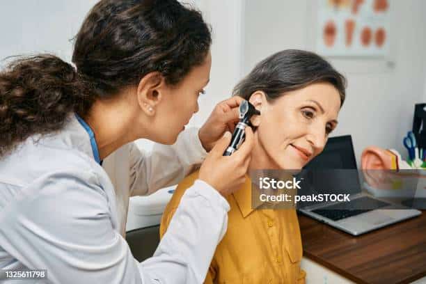 Hearing exam for elderly citizen people. Otolaryngologist doctor checking mature woman's ear using otoscope or auriscope at medical clinic